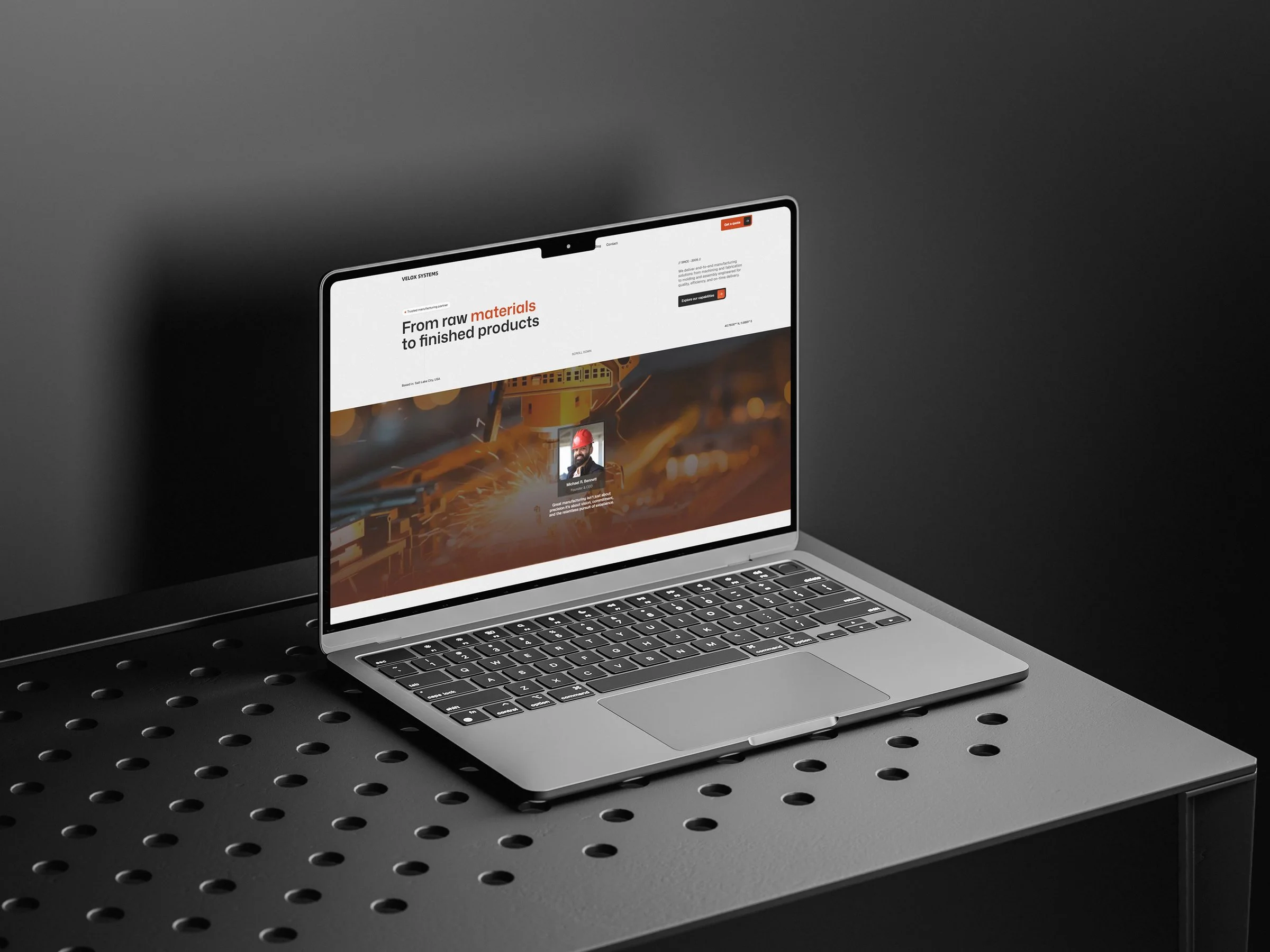 Velox Systems homepage on a laptop sitting on a perforated metal table.